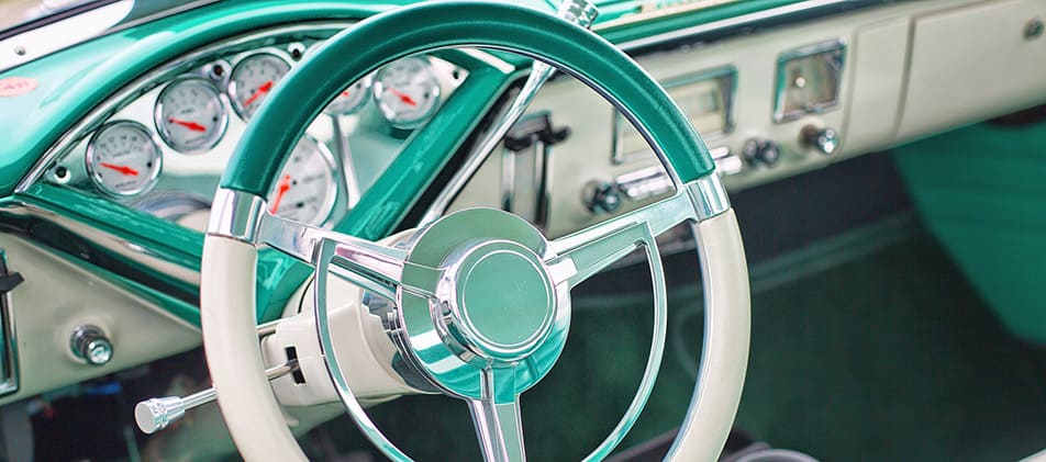 zweifarbiges Lenkrad mit Armaturenanzeigen vom Oldtimer in den Farben Creme und Petrol.